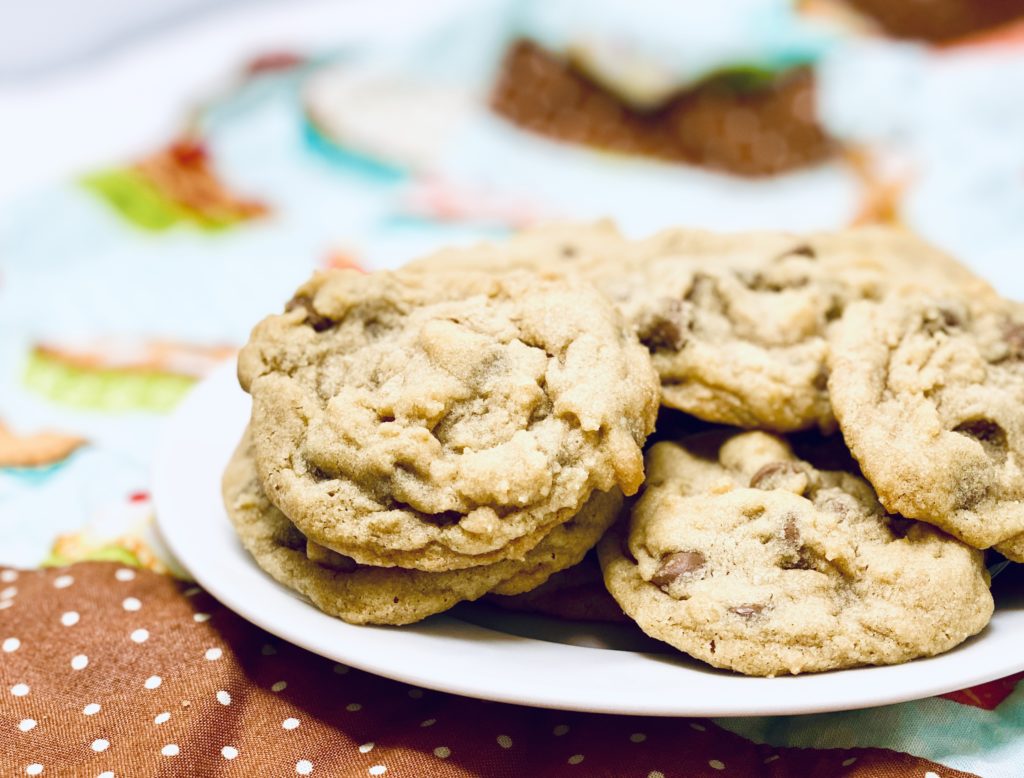 A white plate filled with Egg-Free Chocolate Chip Cookies sitting on a brown and white poka dot trimmed colourful cloth